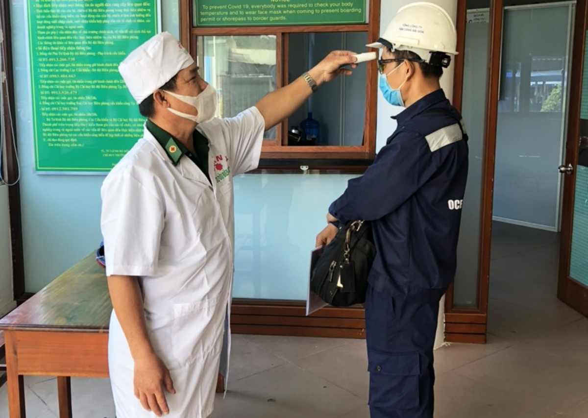Nhân viên làm việc ở cảng Cát Lái đang được bác sĩ quân y kiểm tra thân nhiệt trước khi vào cảng. Ảnh: Hà An.