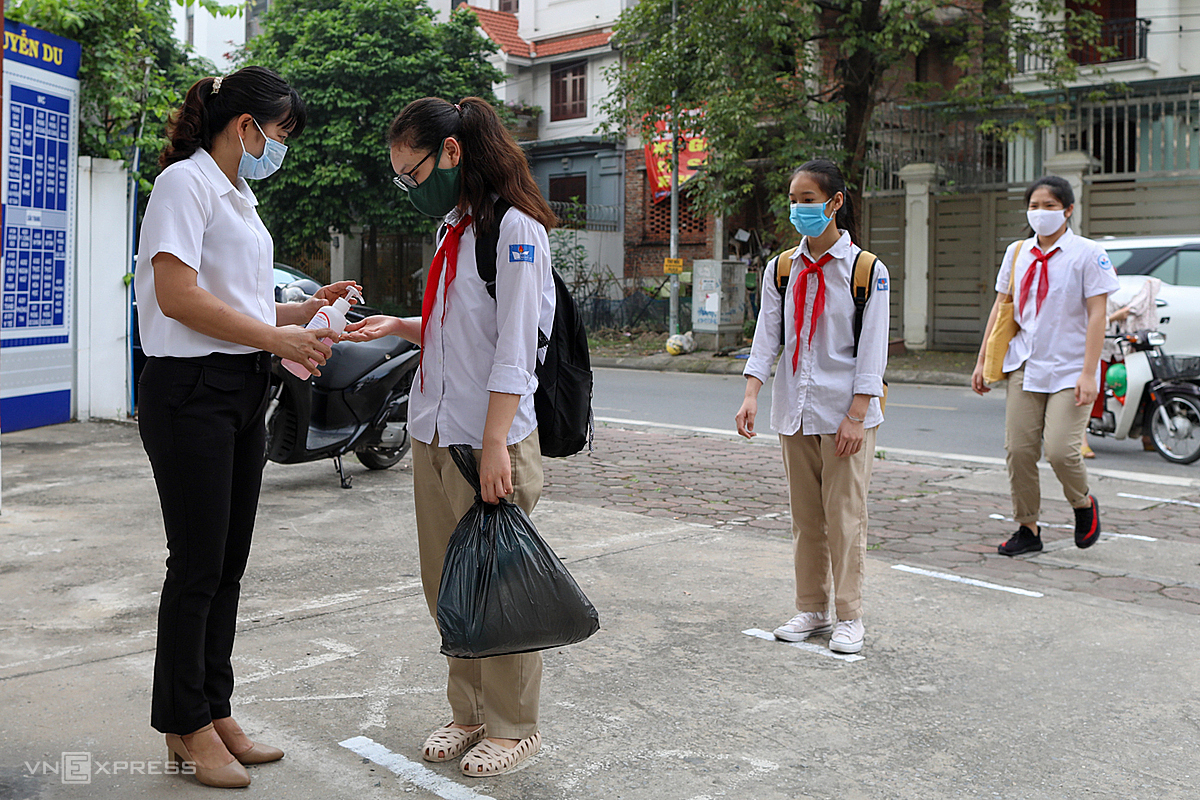 Học sinh trường THCS Nguyễn Du, quận Nam Từ Liêm, Hà Nội đứng giãn cách, xếp hàng đo thân nhiệt trước khi vào trường, tháng 5/2020. Ảnh: Ngọc Thành.