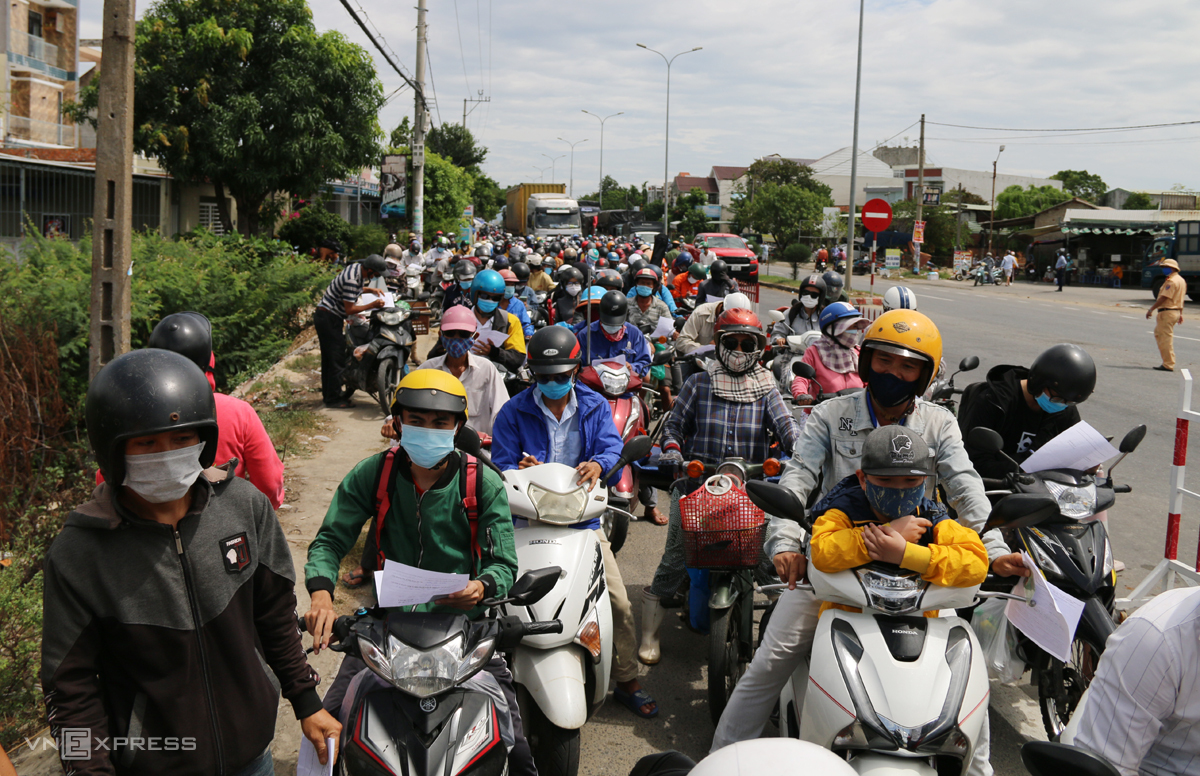 Người dân đứng hàng dài để quá chốt kiểm dịch ở xã Điện Thắng Bắc, thị xã Điện Bàn trước khi vào Quảng Nam, trưa 22/7. Ảnh: Đắc Thành.