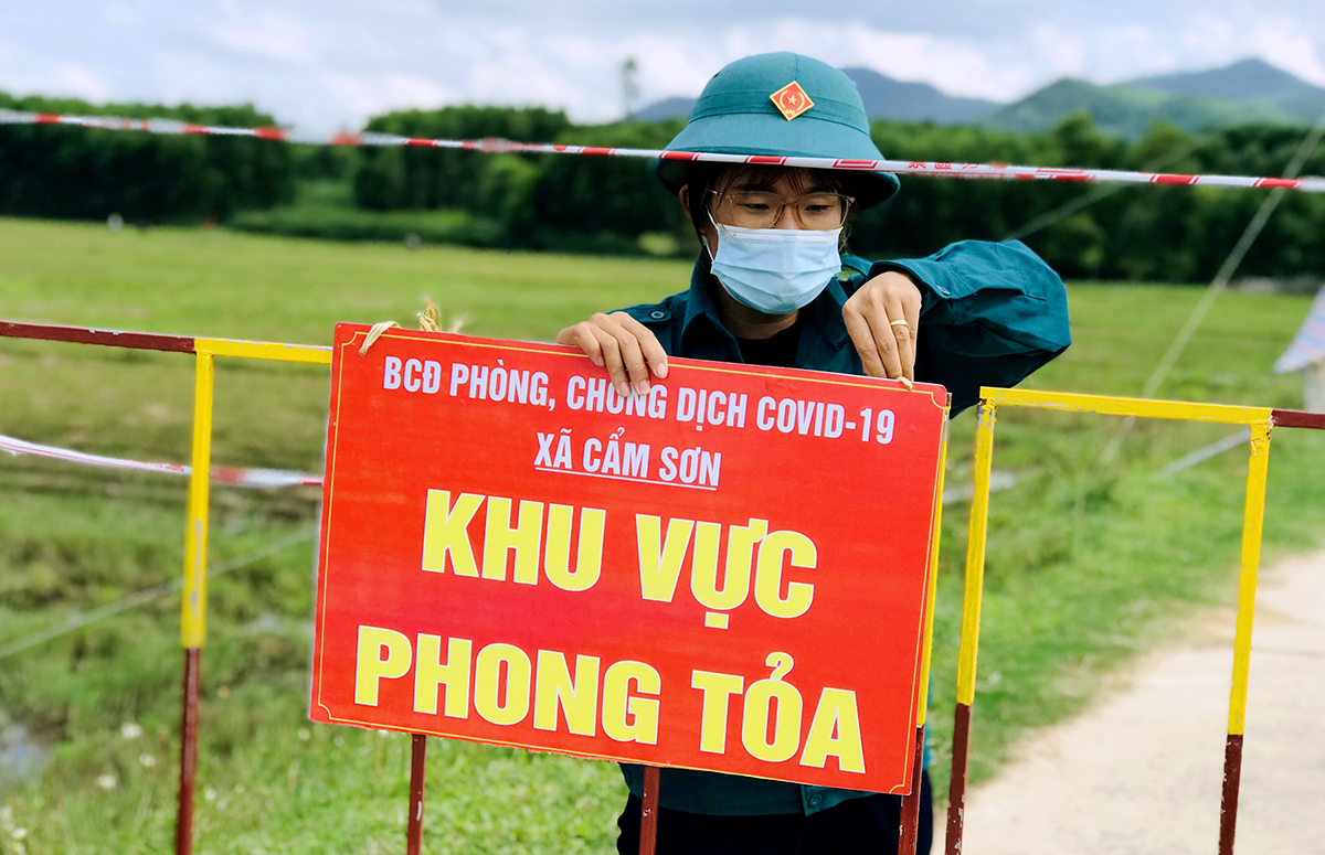 Cán bộ địa phương tháo biển thông báo khu vực phong tỏa tại một chốt kiểm soát ở thôn Vinh Sơn, xã Cẩm Sơn, chiều 16/9. Ảnh: Hùng Lê