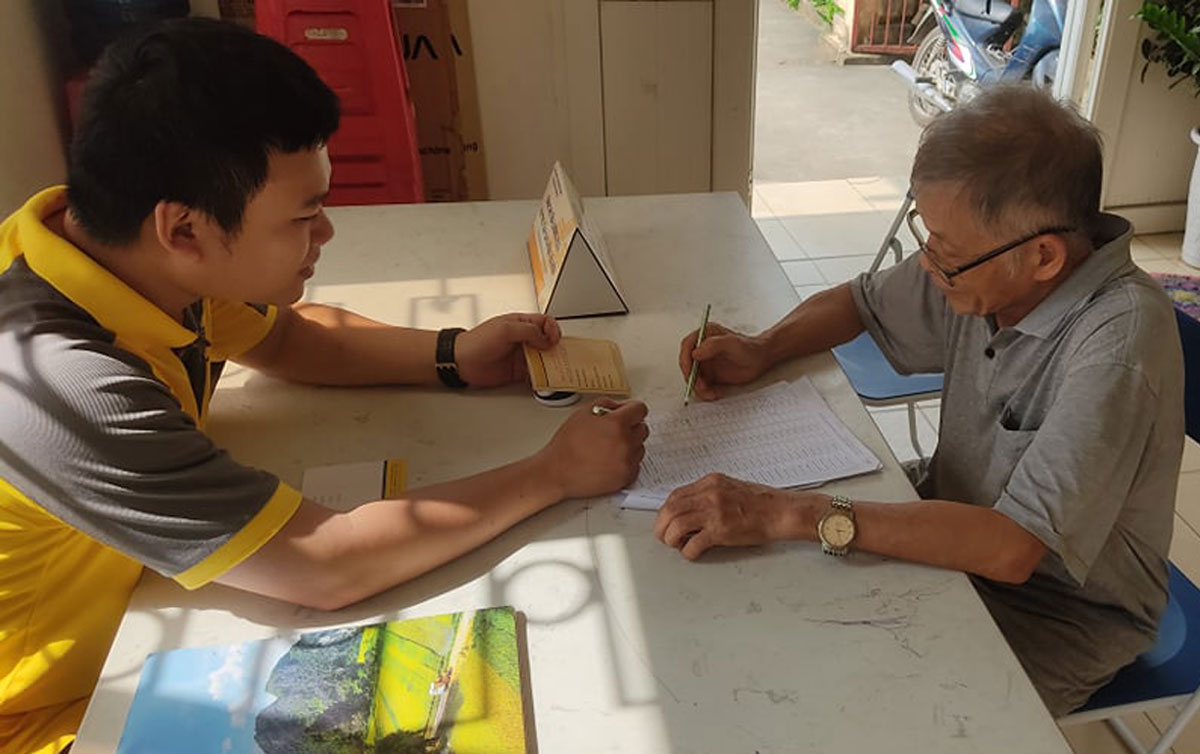 Nhân viên bưu điện hướng dẫn chi trả trợ cấp cho người già trên 80 tuổi, tháng 4/2021. Ảnh: Hà Ngọc
